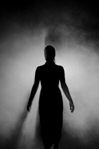 Black and white silhouette of a dancer posing gracefully against a smoky backdrop.